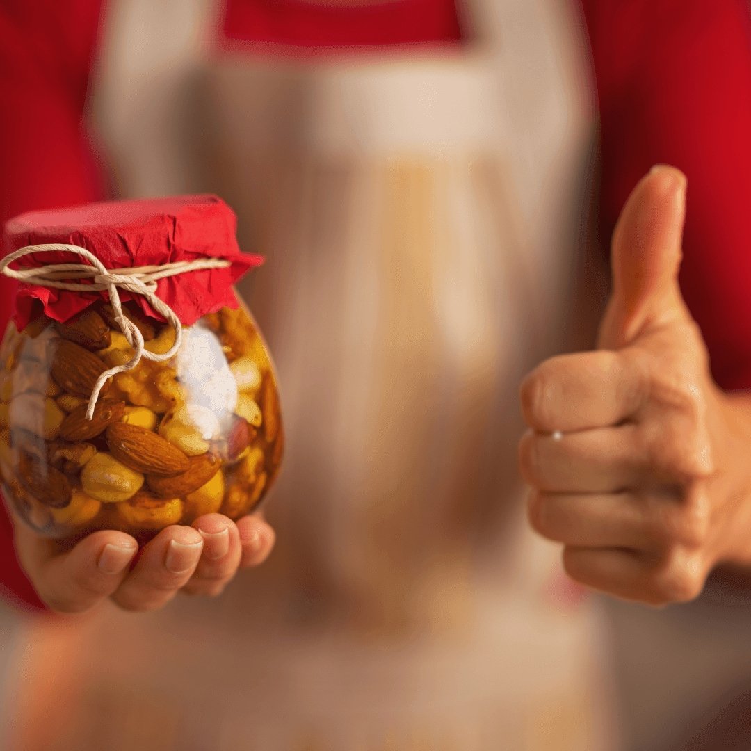 a person holding up a jar with a red, string bound top and giving the thumbs up sign