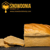 a loaf of brown bread that has been cut into slices at the left hand end with a black background