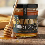 Jar of runny honey with a honey drizzler made of wood